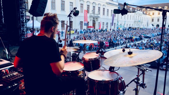 Charly Beat spielt Schlagzeug. Blick von hinten von der Bühne in Ludwigsburg